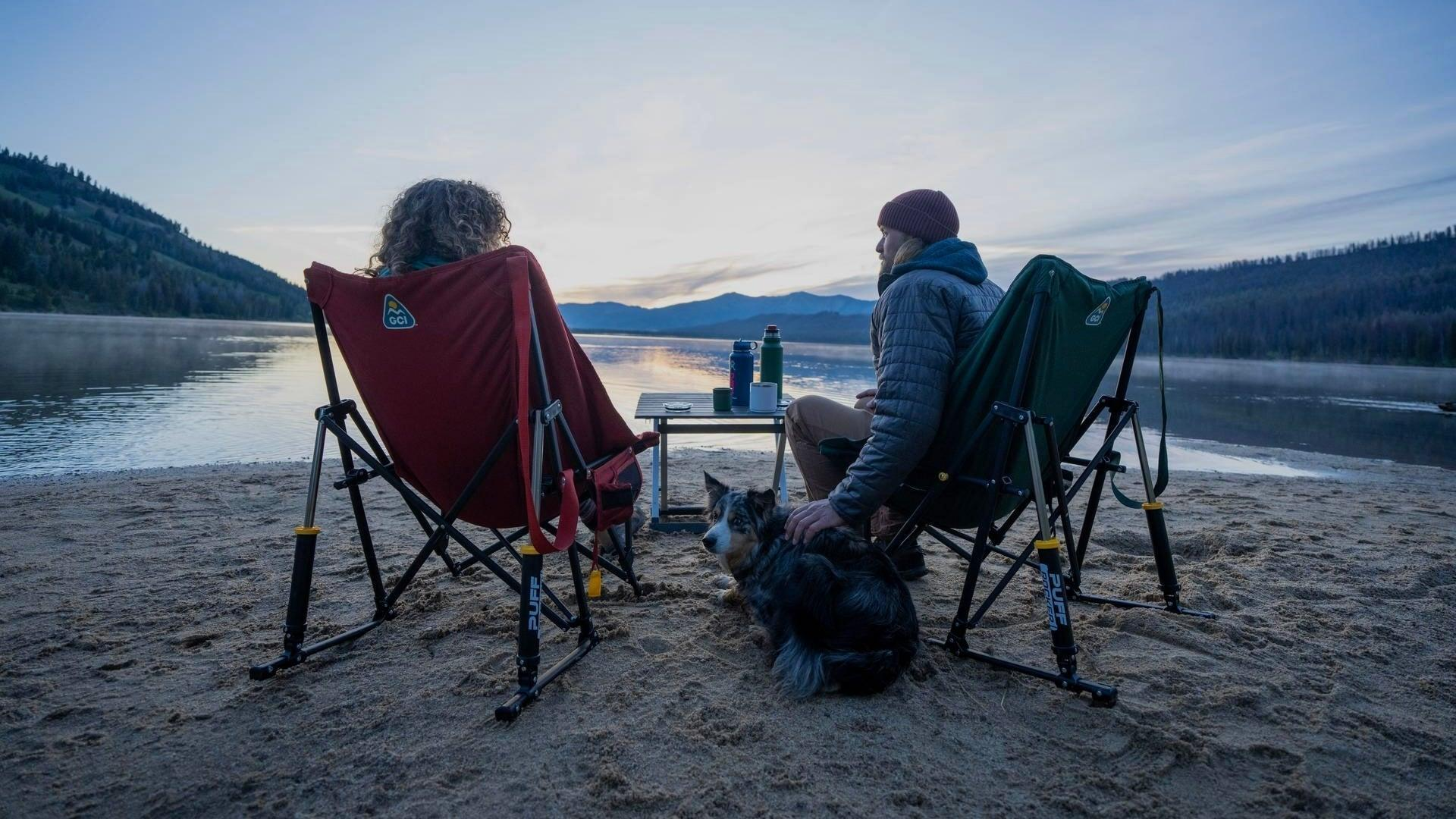 Camping chairs and table at a lakeside campsite
